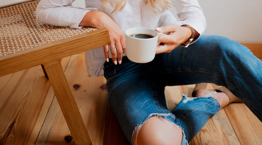 Woman sitting next to a chair with a coffee cup in her hand